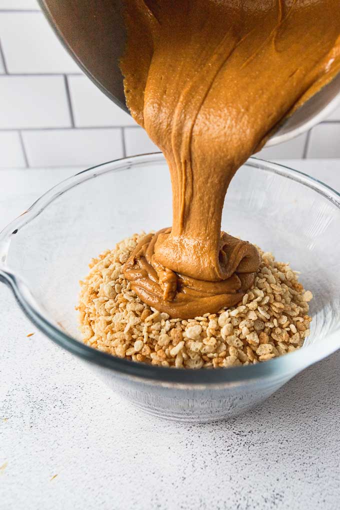 Pouring peanut butter into bowl of Rice Krispies.