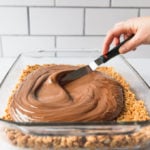 spreading chocolate topping on rice krispie bars