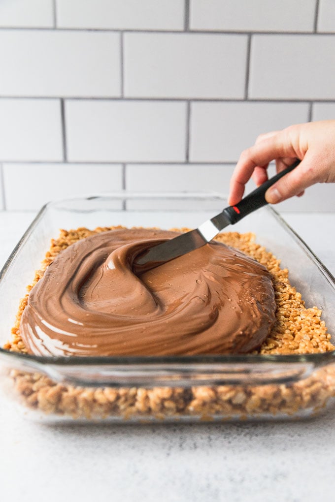 Spreading chocolate topping on rice krispie bars.