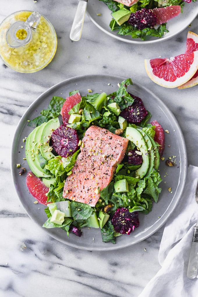 salmon citrus salad with avocado on plate by fork in the kitchen