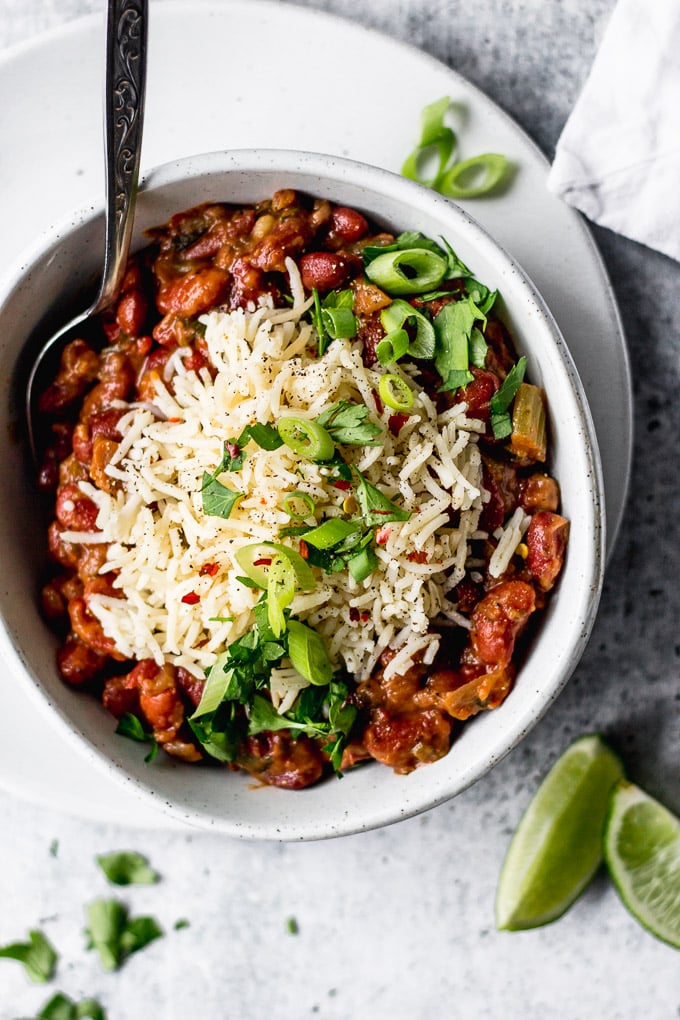 Vegetarian Red Beans and Rice in bowl with green onions and lime by fork in the kitchen