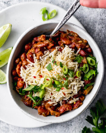 Vegetarian Red Beans and Rice in bowl with green onions and lime by fork in the kitchen