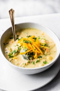 broccoli cauliflower cheddar soup in bowls with baguette by fork in the kitchen