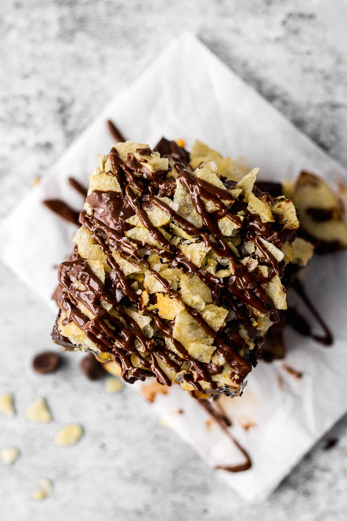 stack of brownies with caramel, potato chips, and chocolate drizzle by fork in the kitchen