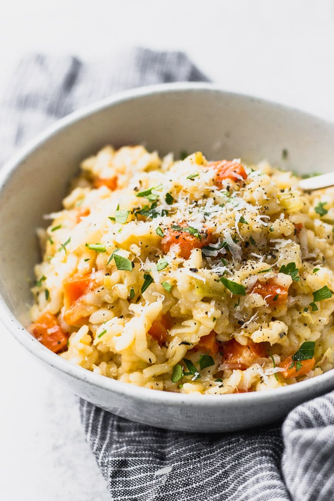 carrot leek risotto in bowls with blue linen by fork in the kitchen