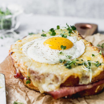 croque madame sandwiches with fried egg on board by fork in the kitchen