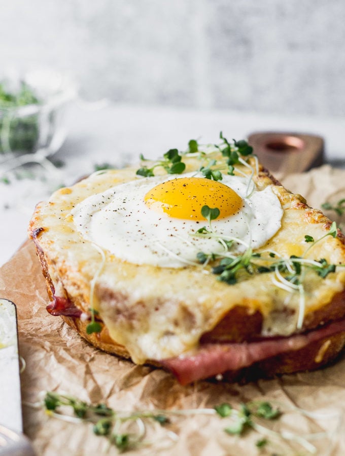 croque madame sandwiches with fried egg on board by fork in the kitchen