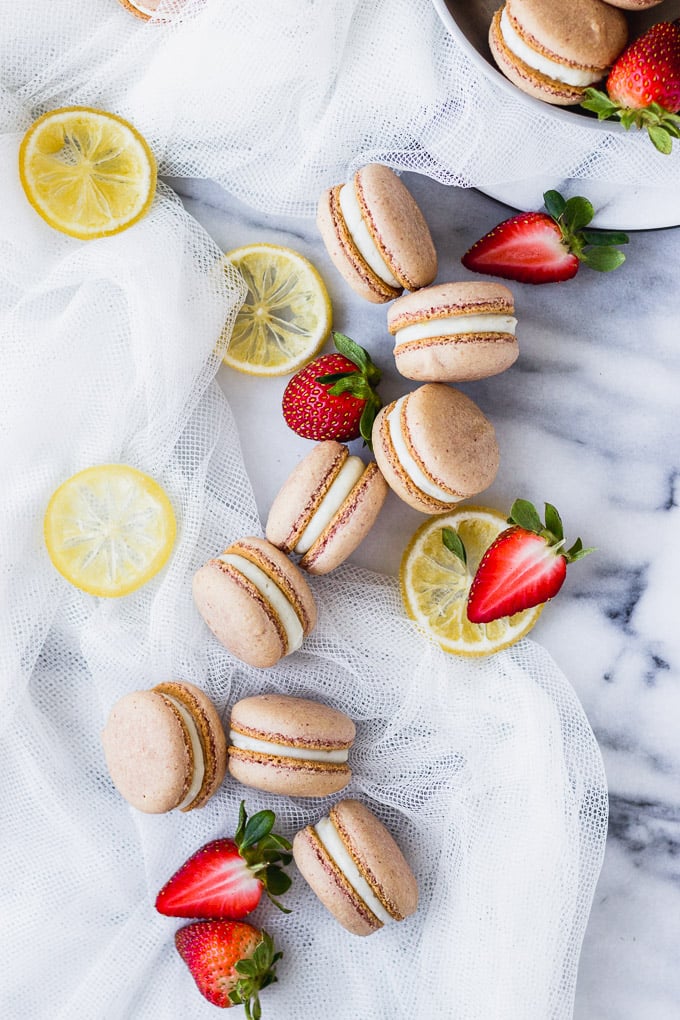 strawberry macarons spread out on marble board