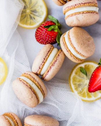 strawberry macarons spread out on marble board