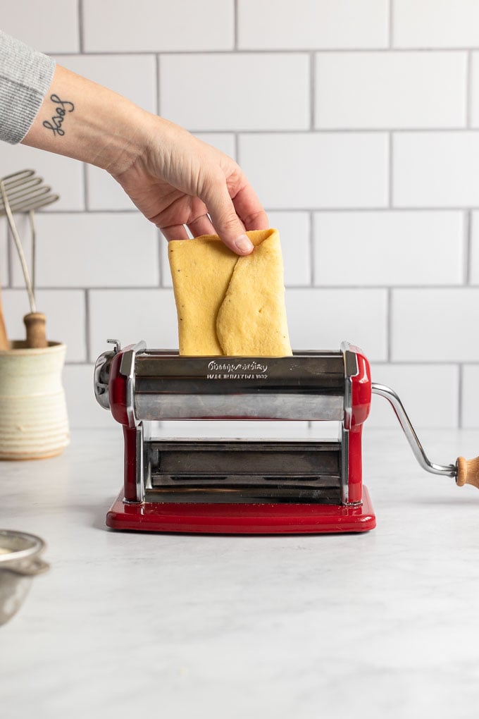 Folded pasta dough going into pasta machine.