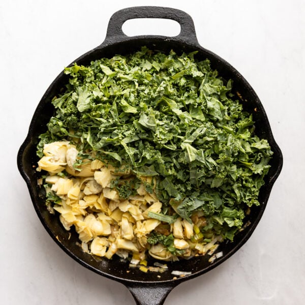 Kale and artichoke added to skillet.