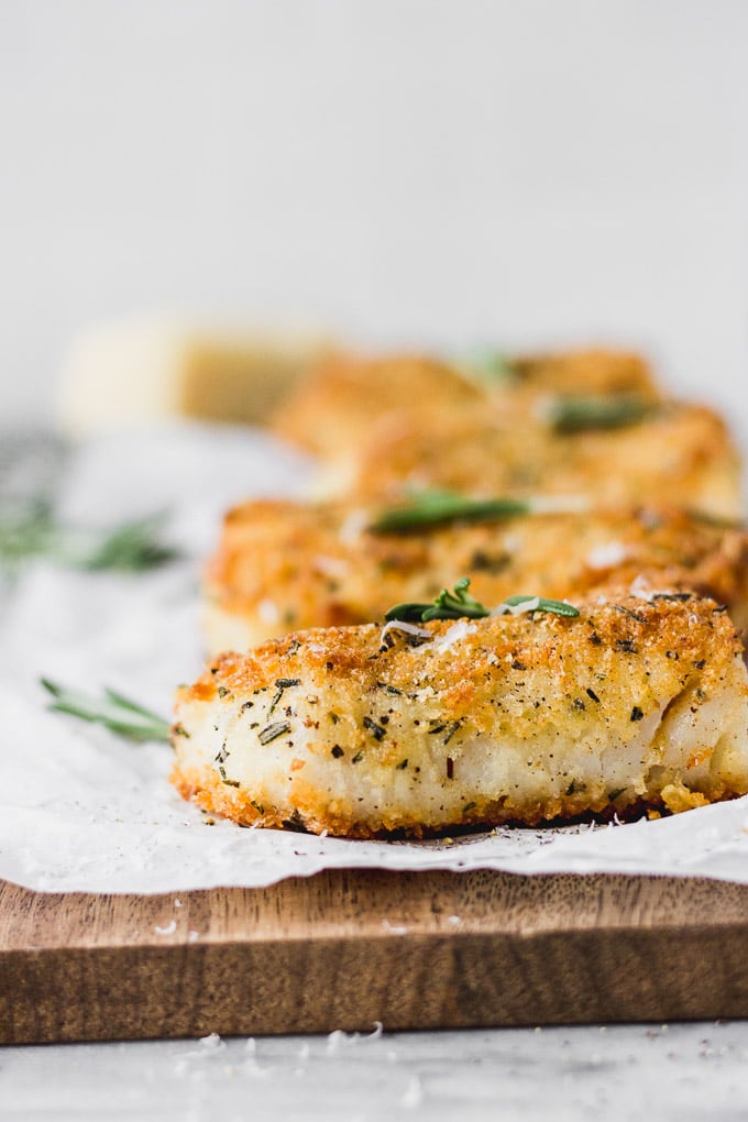 Parmesan Rosemary Crusted Fish on wood cutting board.