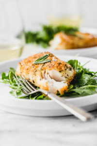 parmesan rosemary crusted cod on arugula with fork