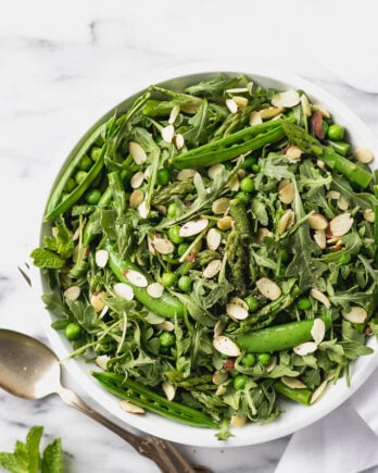 green vegetable salad with asparagus and peas in white bowl
