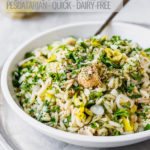 tuna orzo pasta salad in white bowl with spoon by fork in the kitchen
