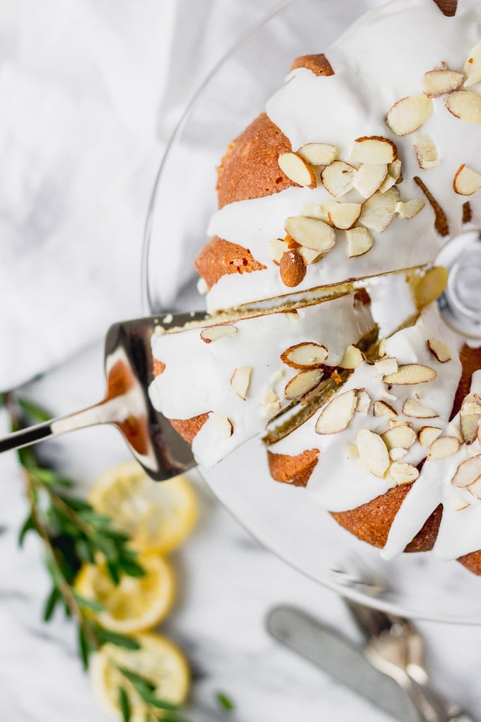 lemon almond cake on clear cake stand with server