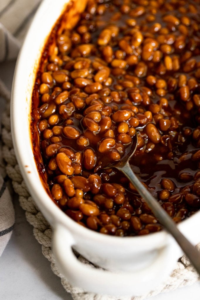 Baked beans in dish with spoon.