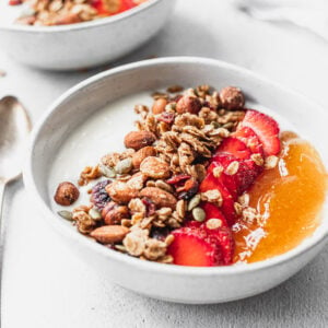 bowl of cinnamon granola with strawberries and apricot jam