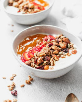 bowl of cinnamon granola with strawberries and apricot jam