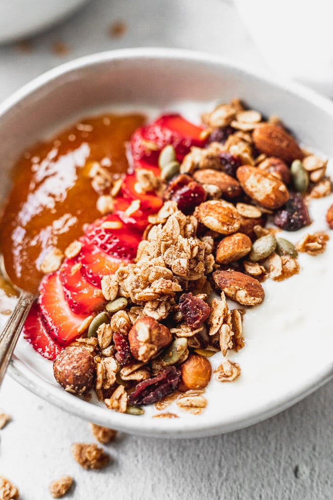up close bowl of cinnamon granola with strawberries and apricot jam
