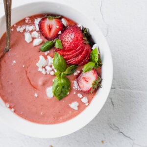 white bowl with pink strawberry basil gazpacho with spoon
