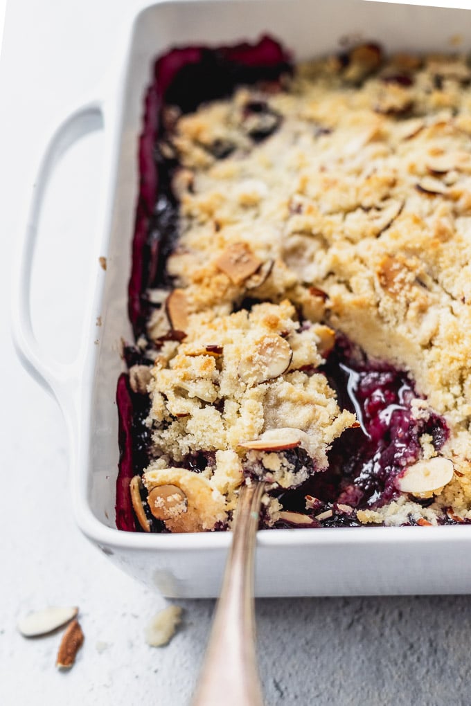 blueberry almond crisp in a white baker and spoons