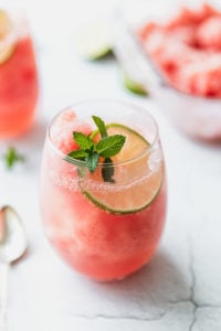 wine glass with watermelon granita, mint, and a lime with a spoon