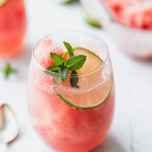 wine glass with watermelon granita, mint, and a lime with a spoon