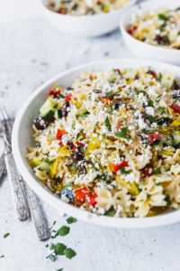 mediterranean pasta salad in white bowl with forks