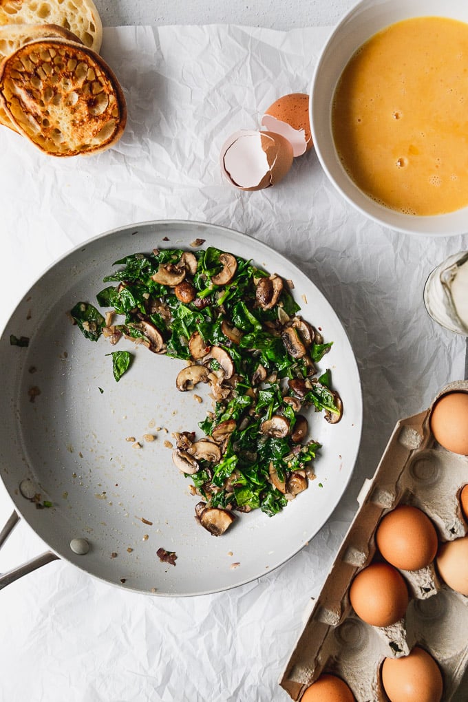 pan with spinach and mushrooms next to eggs