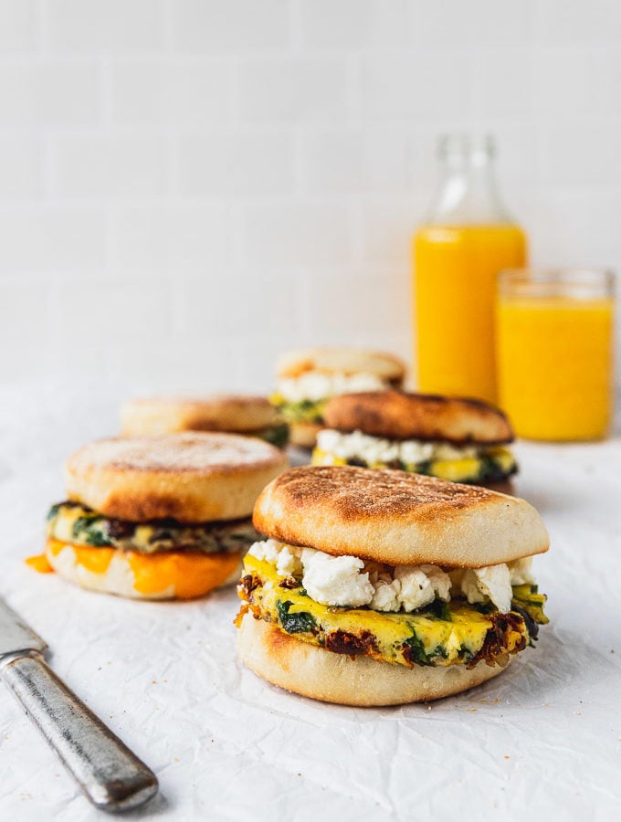 rows of breakfast sandwiches with knife and orange juice glasses