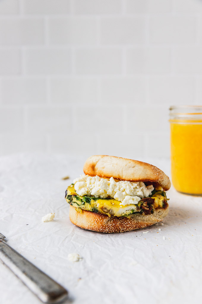 english muffin with egg and feta cheese next to orange juice