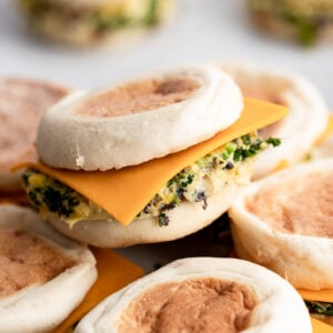 Breakfast sandwich with slice of cheese hanging out on english muffin.