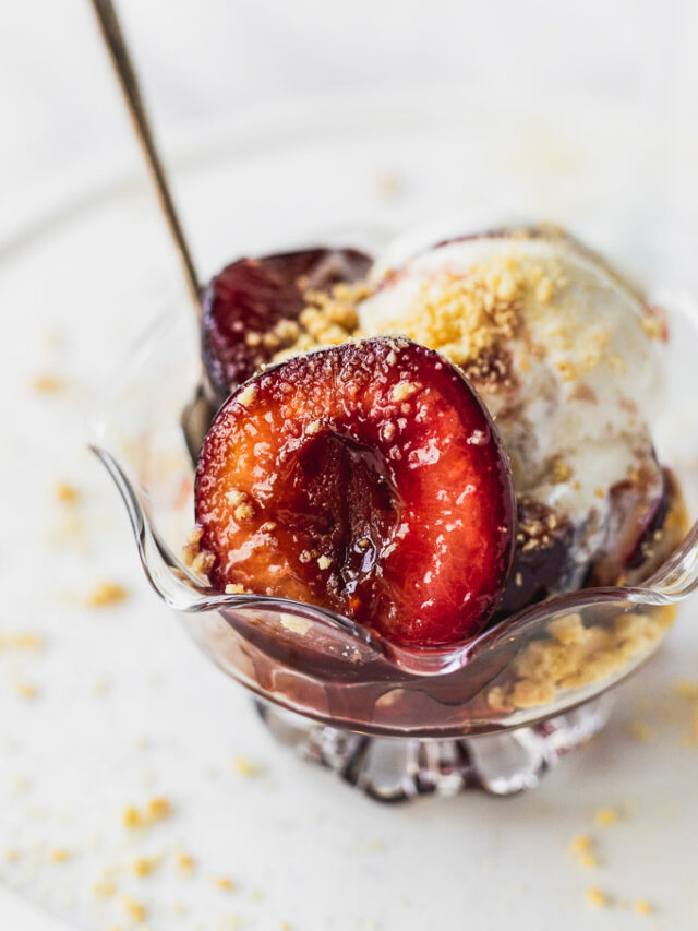 Sauteed plums in bowl with ice cream and spoon.