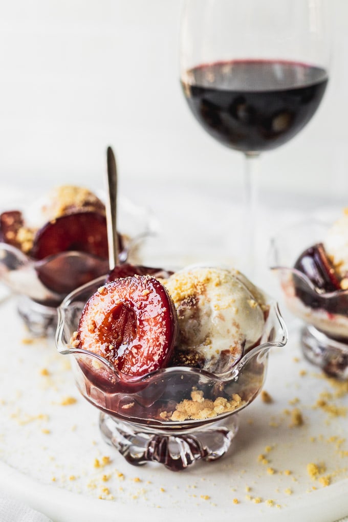 bowl of sauteed fresh plum dessert with ice cream and wine sauce with spoon