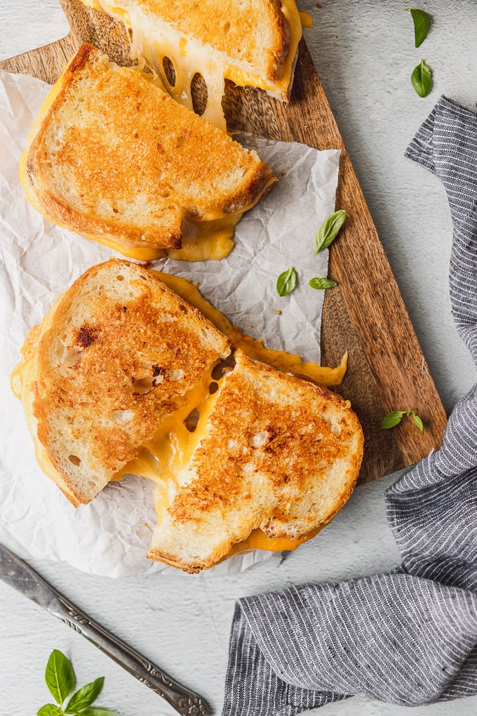 Two grilled cheeses cut in half with cheese pull.