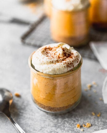 pumpkin mousse with whipped cream in jar next to spoon