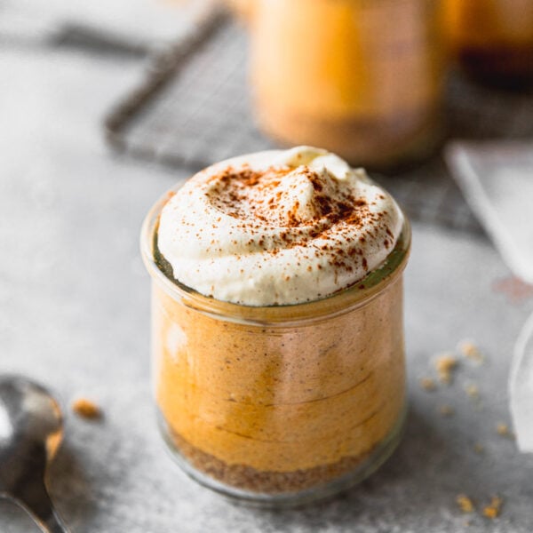 pumpkin mousse with whipped cream in jar next to spoon