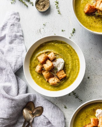 three bowls of broccoli soup with croutons