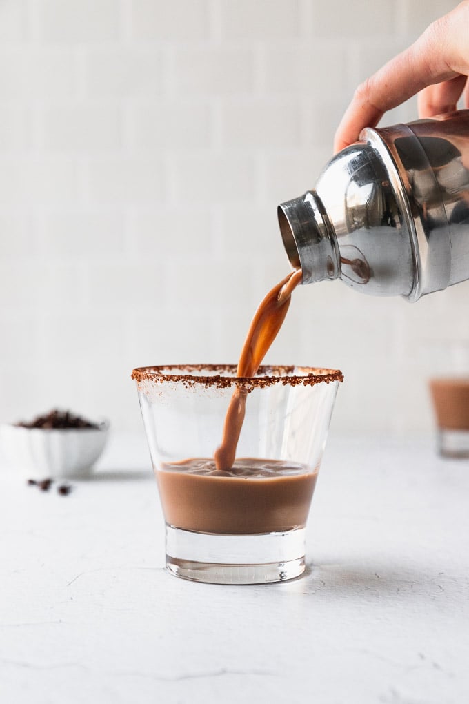 Pouring drink into a cocoa rimmed martini glass from shaker