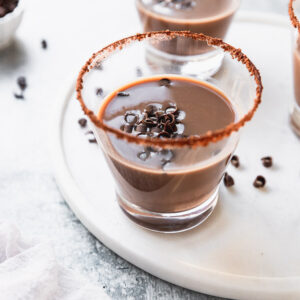 glass of chocolate white russian with chocolate swirls as garnish on white tray