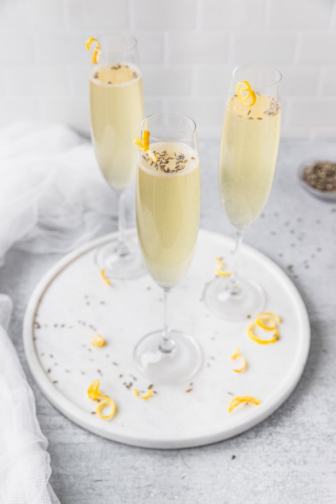 three champagne glasses with lavender and lemon twist