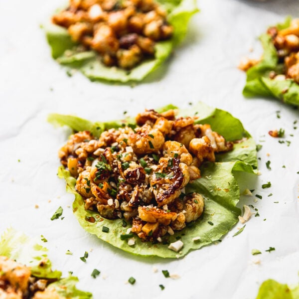 five lettuce wraps with cauliflower on white background with teriyaki sauce
