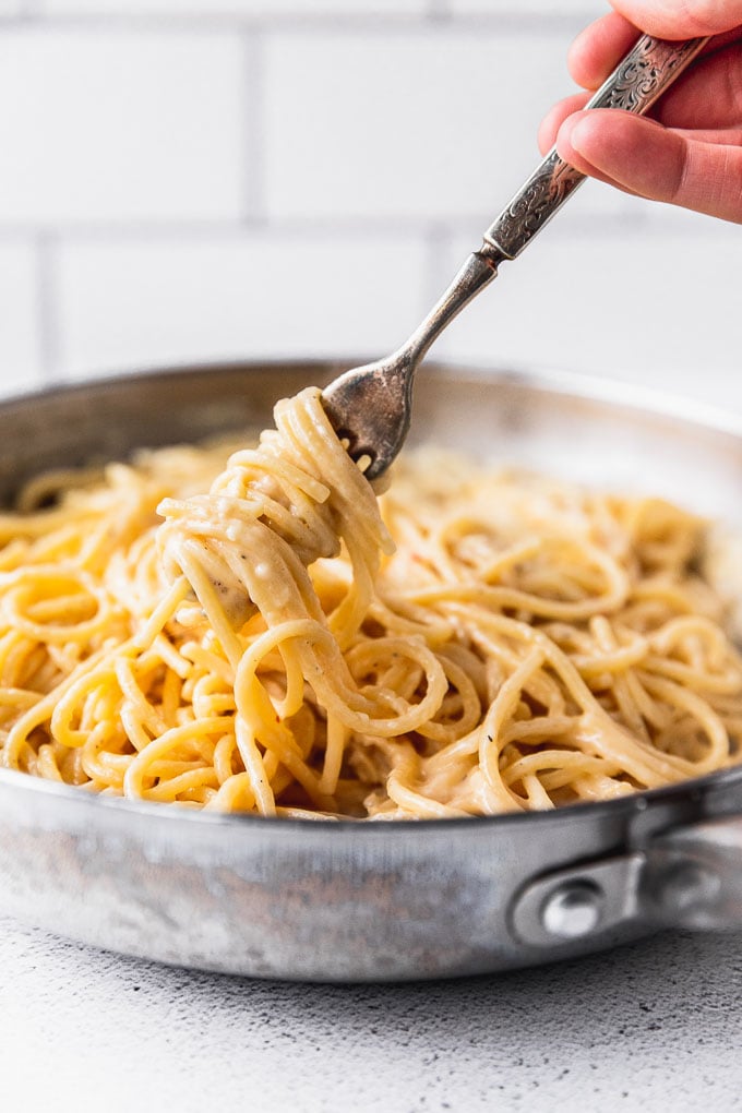 Fork twirling spaghetti pasta in large skillet.
