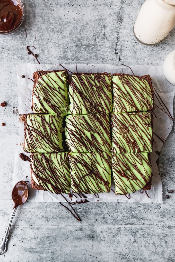brownies topped with green peppermint frosting cut into squares with drizzled chocolate