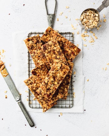 pile of granola bars on cooling rack with knife and oats next to it