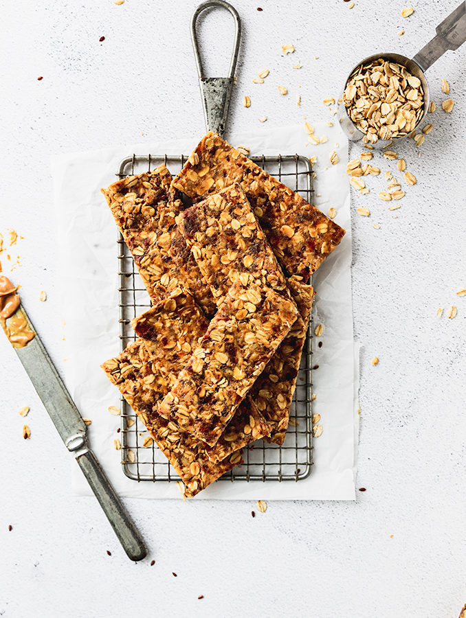 pile of granola bars on cooling rack with knife and oats next to it