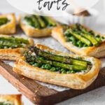 puff pastry tart on parchment paper on wood serving tray with asparagus and peas