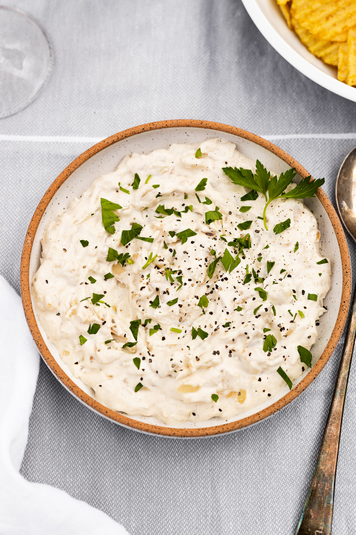 Bowl of onion dip with parsley garnish.