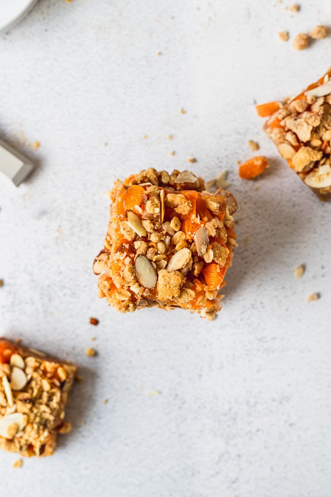 overhead view of apricot bar with almond crumble next to two other bars and a knife